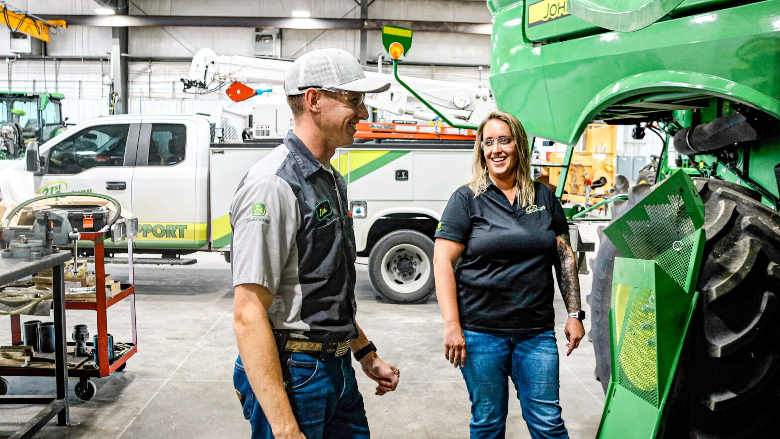 Lonnie, standing with a technician, in the repair bay of 21st Century Equipment.